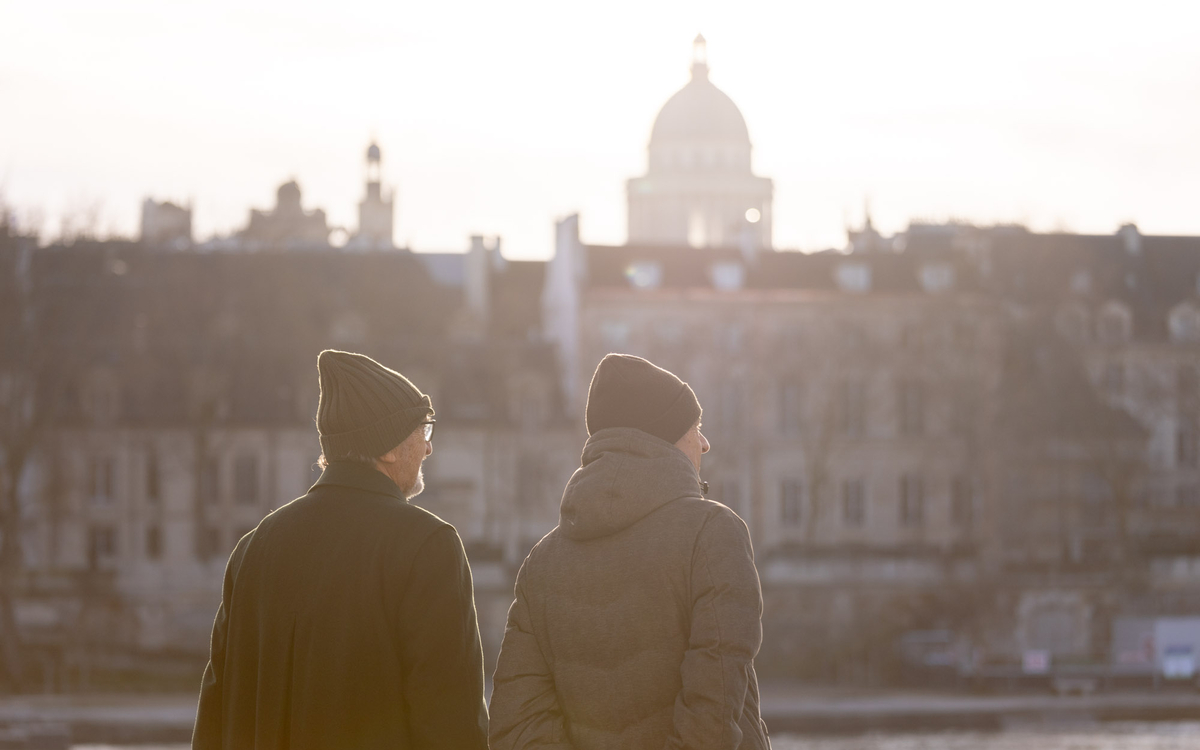 Deux personnes se promènent dans la lumière hivernale de Paris.