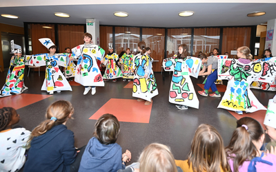 Des enfants défilent avec des robes en papier aux couleurs vives peintes par eux