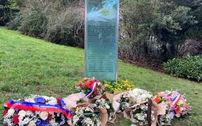 photo de la plaque commémorative entourée de bouquets de fleurs