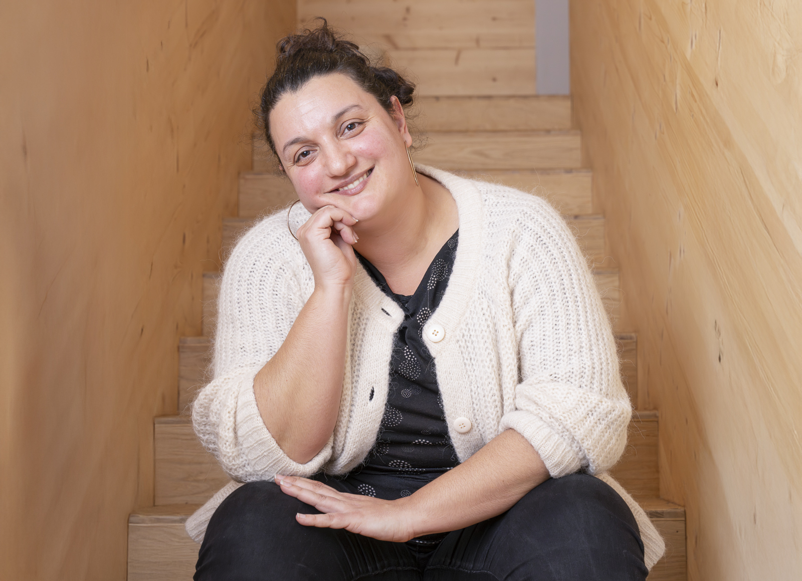 Une femme en gilet blanc assise dans sur des marches d'escalier