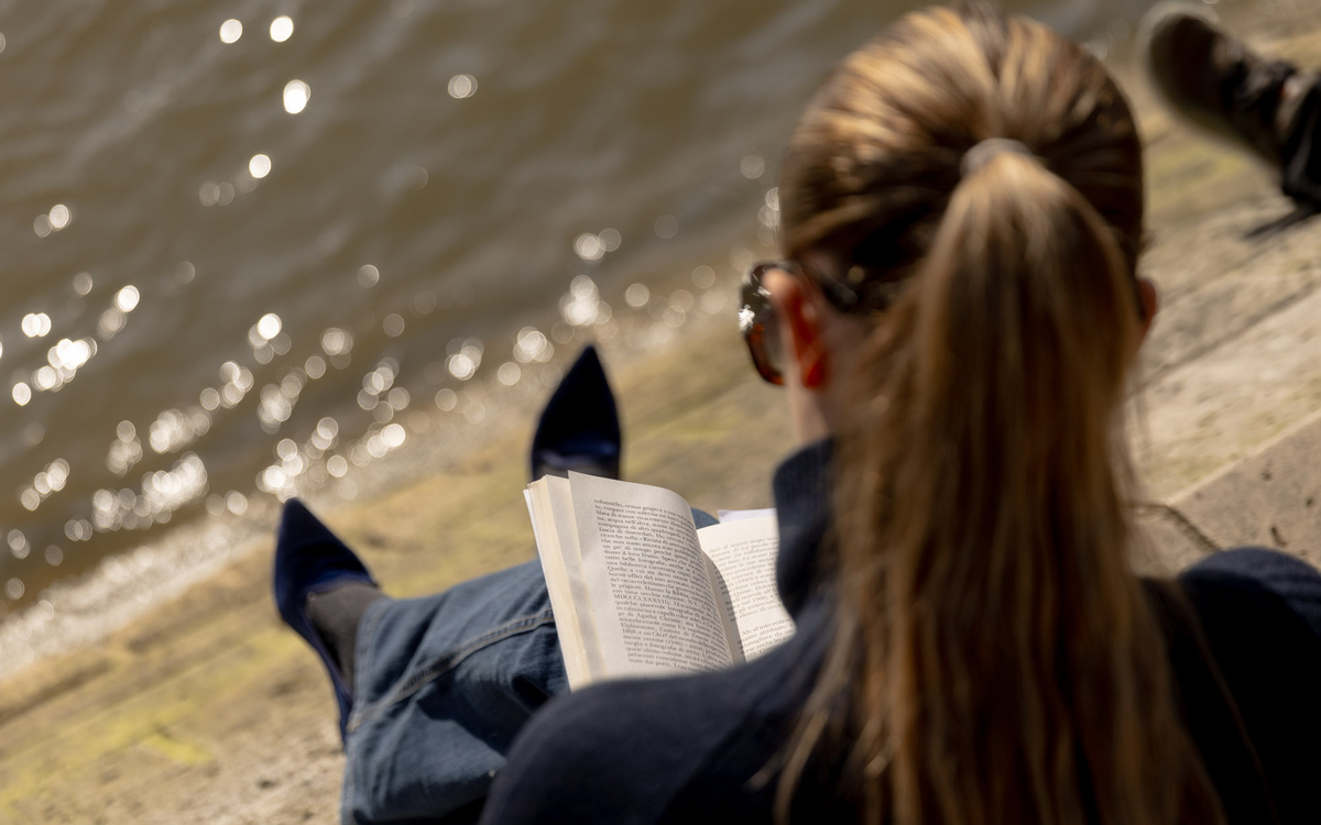 Une personne lit au bord de l'eau 