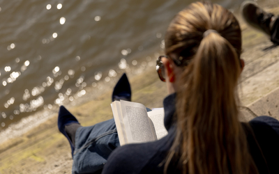 Une personne lit au bord de l'eau 