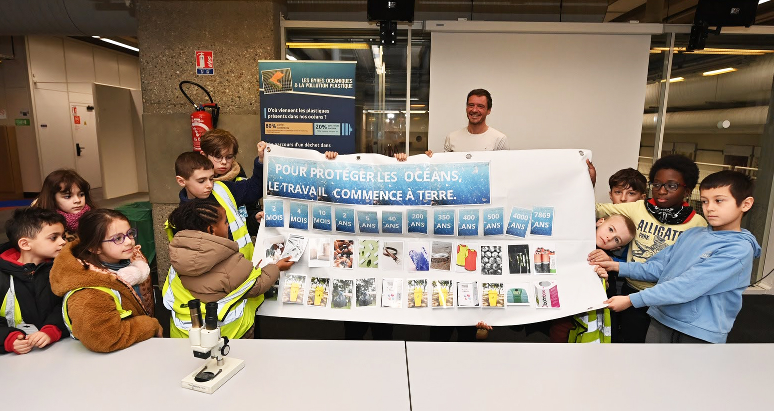 des enfants tiennent une affiche sur laquelle est inscrit "Pour protéger les océans le travail commence à terre"