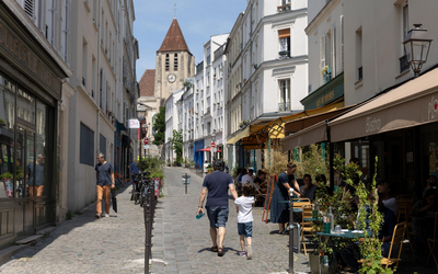 Photo de piétons flânant dans la rue Saint-Blaise, avec l'église Saint-Germain de Charonne en fond