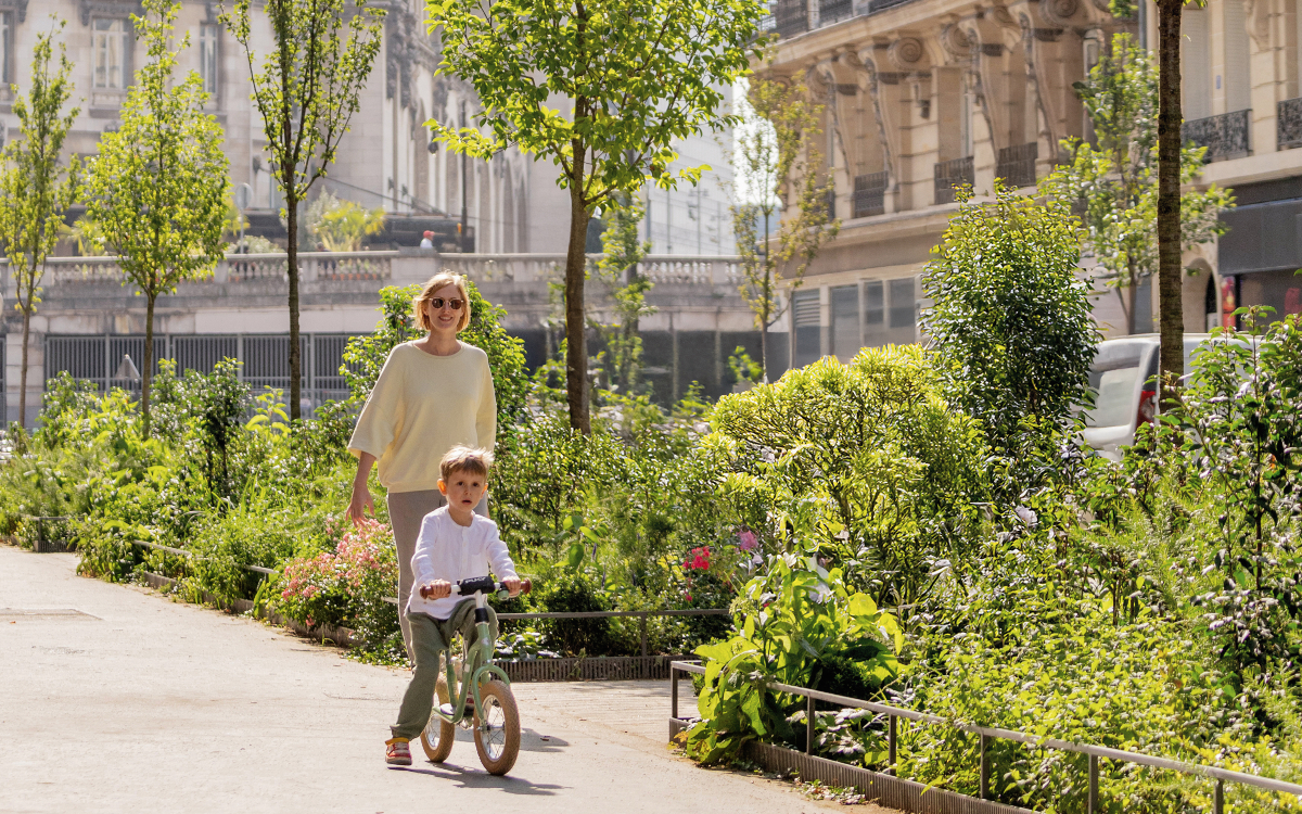 Une personne et un enfant à vélo se promènent dans une rue aux écoles.