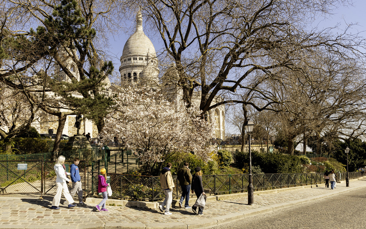Des personnes se promenant devant un cerisier en fleurs sur le parvis de la basilique du Sacré-Cœur.