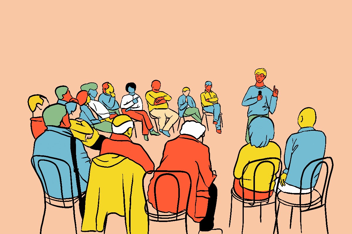 L'image représente une scène de réunion ou de formation. Un groupe de personnes, d'environ 12 à 15 individus, sont assises sur des chaises, vue de dos. Elles portent des vêtements de différentes couleurs : bleu, jaune, rouge, vert. Un intervenant, portant un t-shirt bleu, se tient debout et semble parler ou donner une présentation. Le fond est d'un ton pêche doux, créant une ambiance chaleureuse et calme.