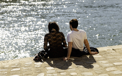 Deux personnes assises sous le soleil printanier, face à la Seine. 