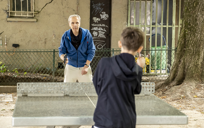 Une personne âgée et un enfant qui jouent au tennis de table