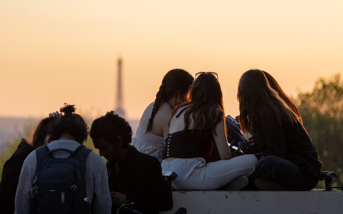 Des adolescents regardent le soleil couchant depuis le parc de Belleville.