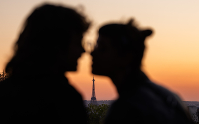 Deux personnes en contre jour sur fond de tour Eiffel et de coucher de soleil. 