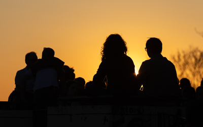 Des personnes regardent le soleil couchant depuis le parc de Belleville.