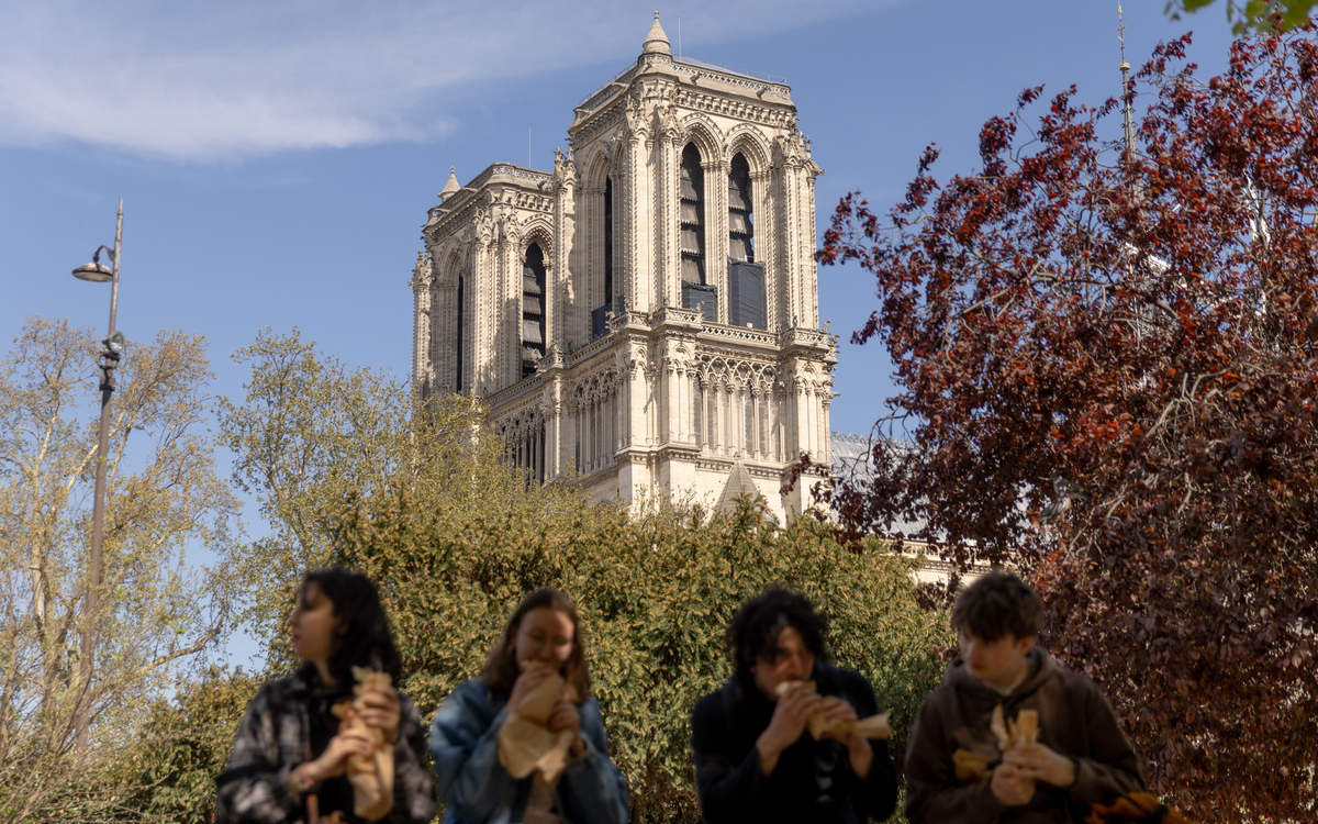 Des adolescents prennent leur pause déjeuner devant Notre dame.