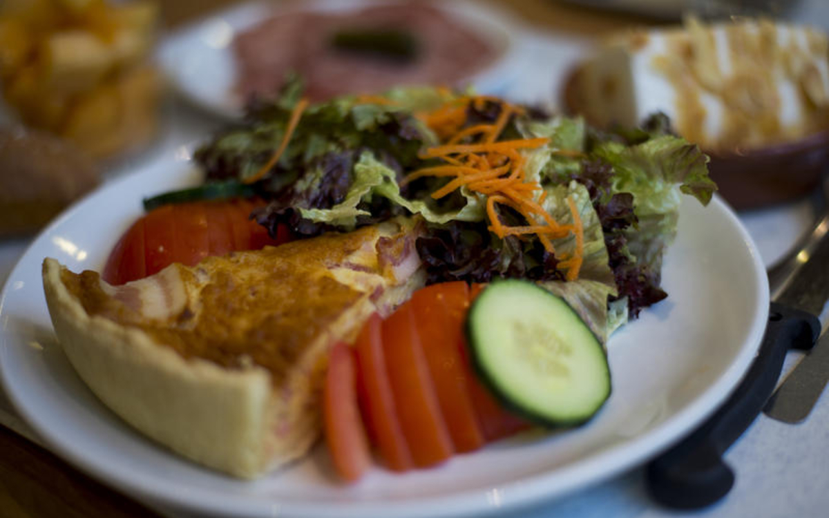 Quiche, tomates, concombre et salade dans une assiette blanche