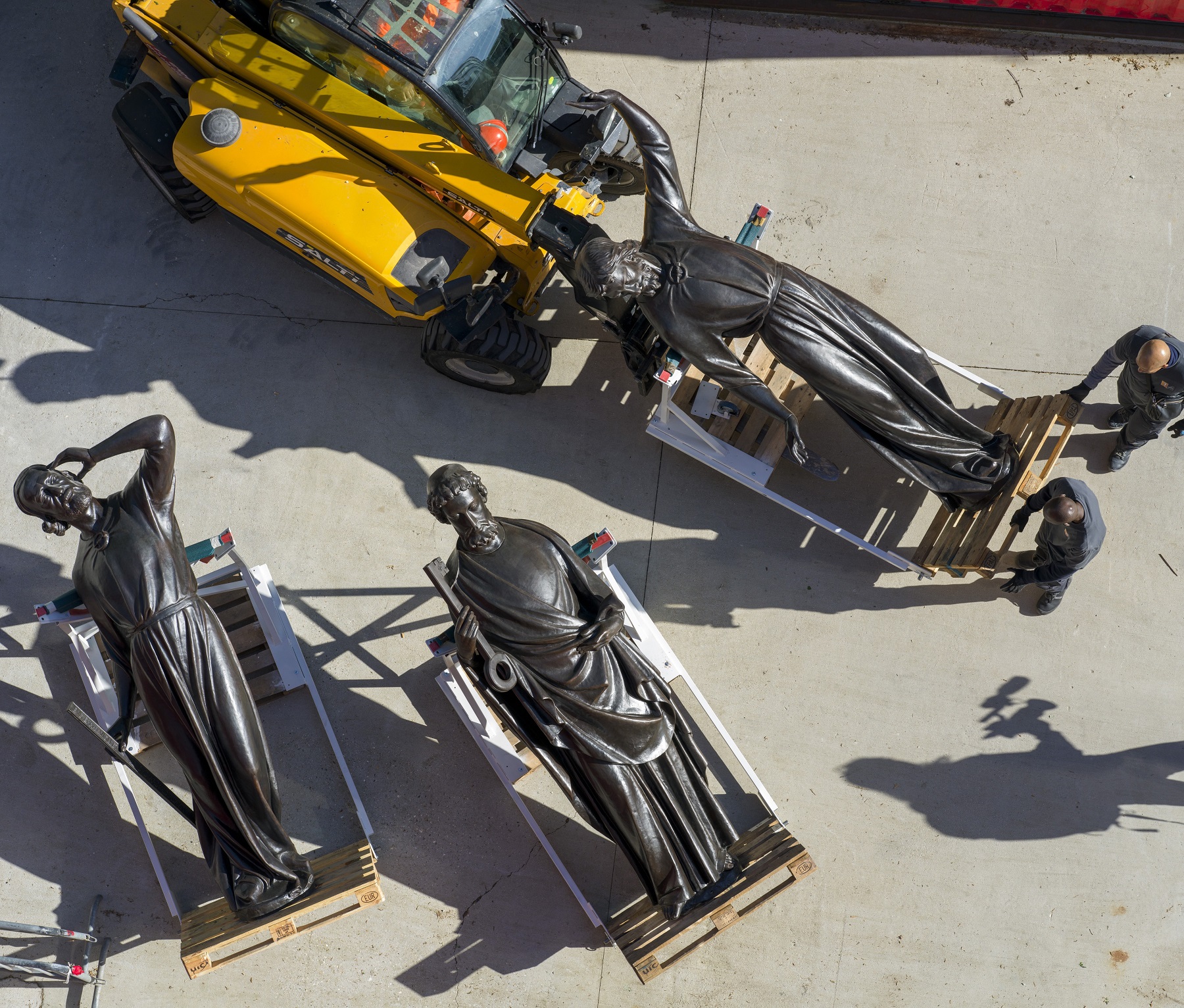 des ouvriers  déplacent les statues