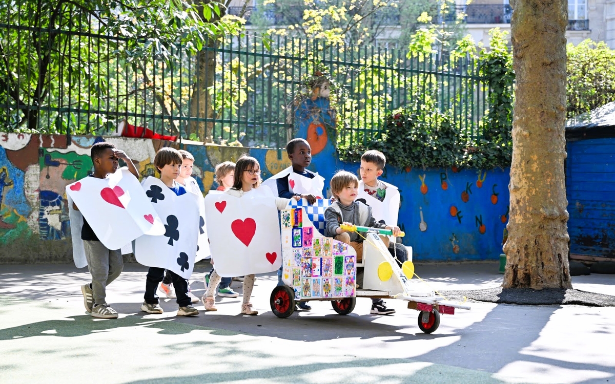 un groupe d'enfants déguisés en carte à jouer pousse le pushcar qu'il a construit