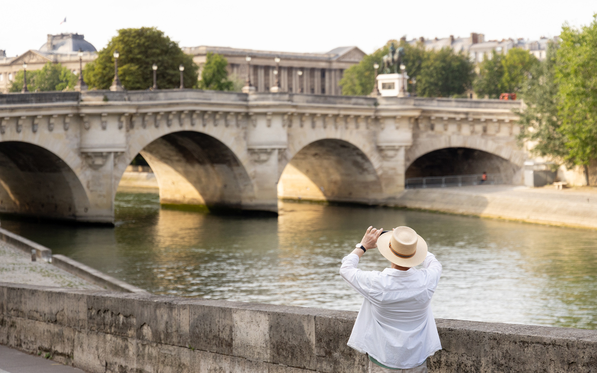 Une touriste prenant une photo du pont neuf.