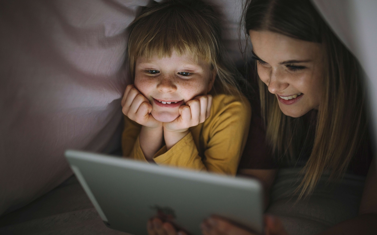 Une petite fille et une plus grande qui regardent un écran