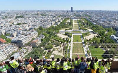 Des enfants observent la vue sur le champ de Mars et la gare Montparnasse au loin depuis le deuxième étage de la tour Eiffel