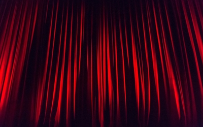 Un rideau de théâtre rouge vif, occupe toute l'image avec un jeu d'ombre