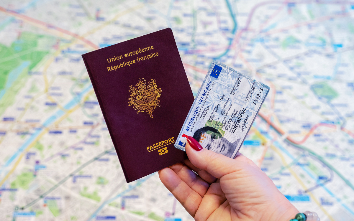 Passeport et carte nationale d'identité électronique (CNI-E) présentés par une main féminine sur fond de plan du métro parisien