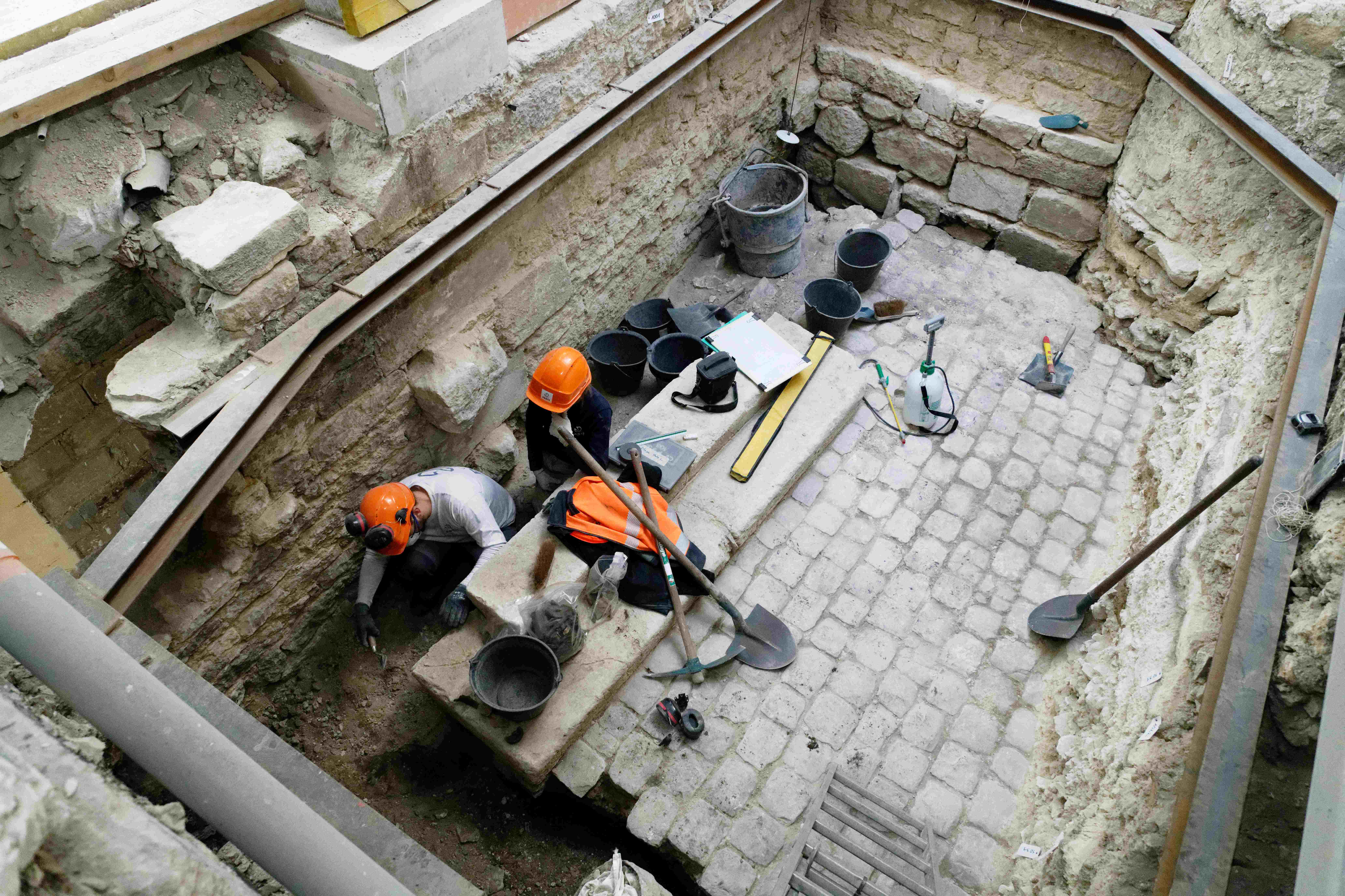 Deux archéologues mettent au jour un pavement en pierre.