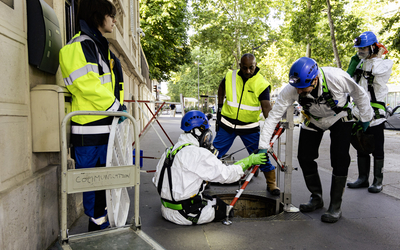 Les égoutiers en tenue amorcent leur descente dans les égouts de Paris, dans le 7ᵉ arrondissement.