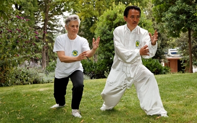 Deux personnes faisant du Qi Gong dans un parc