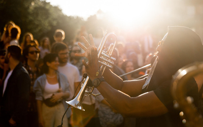Le soleil se couche sur une scène ou un tromboniste joue au milieu d'habitants dans un quartier