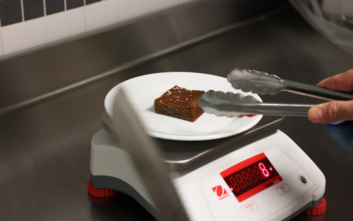 une part de gateau au chocolat sur une balance de cuisine