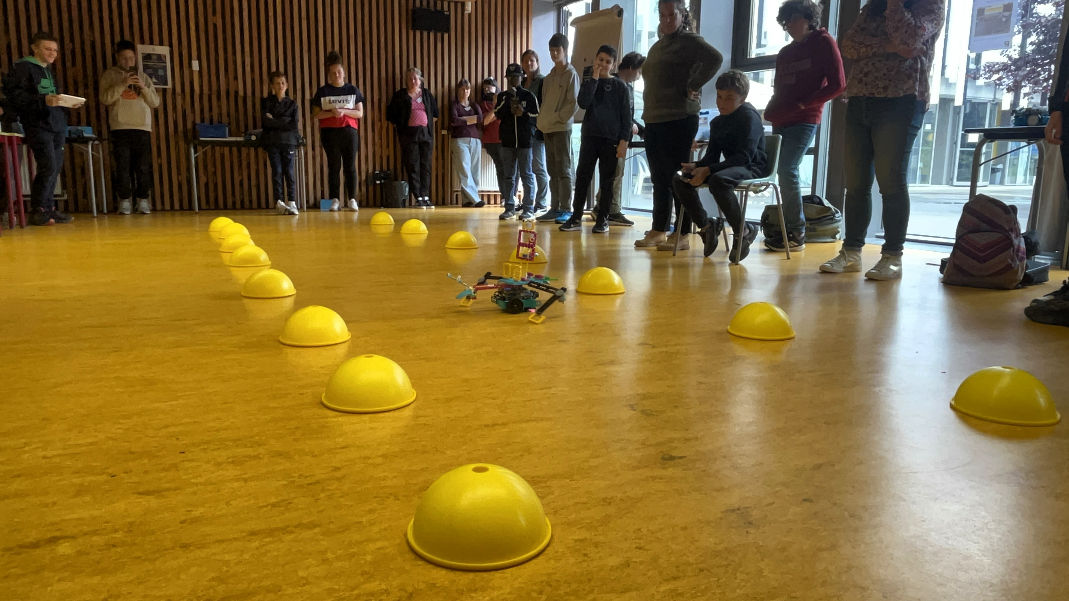 un robot téléguidé par un collégien s'avance sur le podium pour être présenté au jury