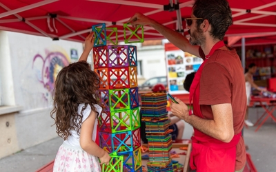 Un animateur propose un jeu de construction à une jeune fille et crée une grande tour bariolée