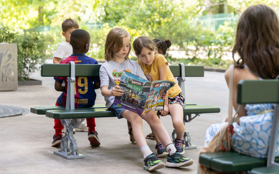Des enfants assis sur un mini banc Davioud.