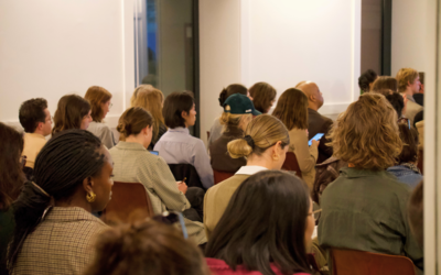 Plusieurs personnes rassemblées pour un évènement sur l'entreprenariat écoutent une conférence
