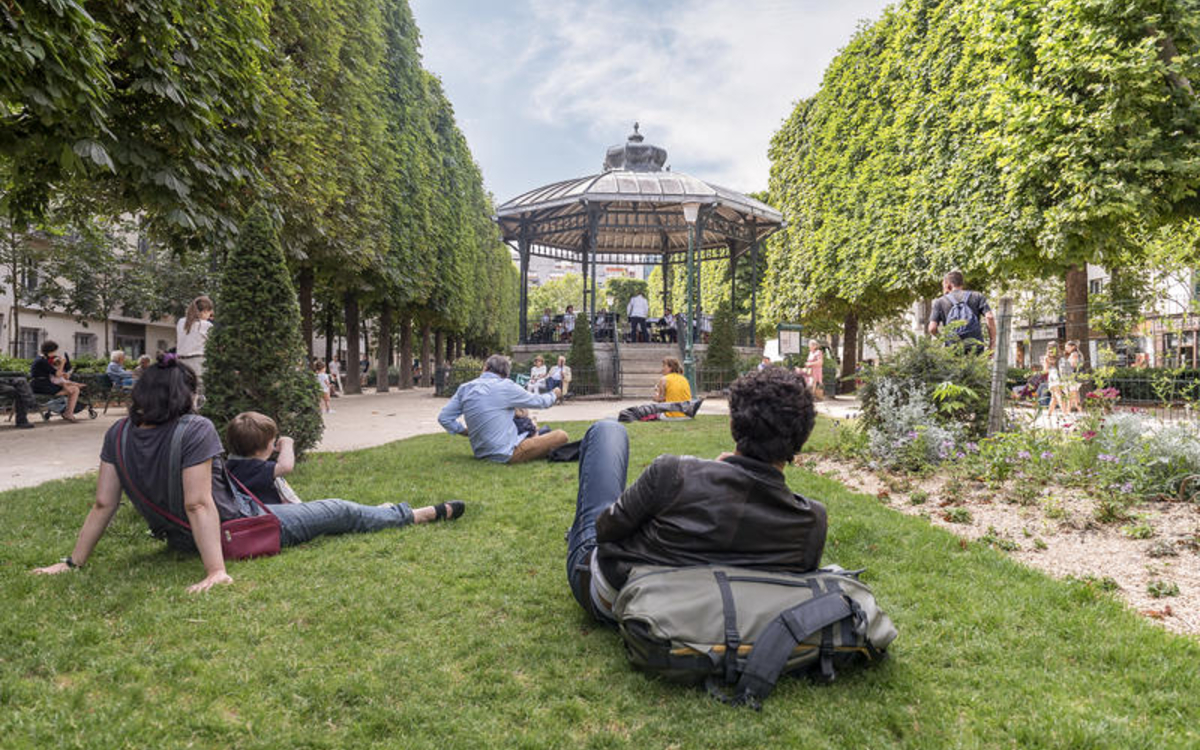 des Parisiennes et des Parisiens écoutent le concert d'une formation installée dans un kiosque parisien