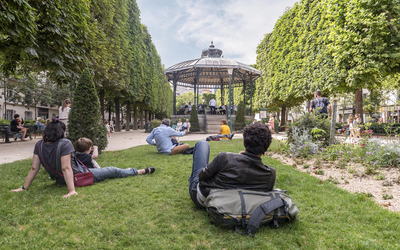 des Parisiennes et des Parisiens écoutent le concert d'une formation installée dans un kiosque parisien