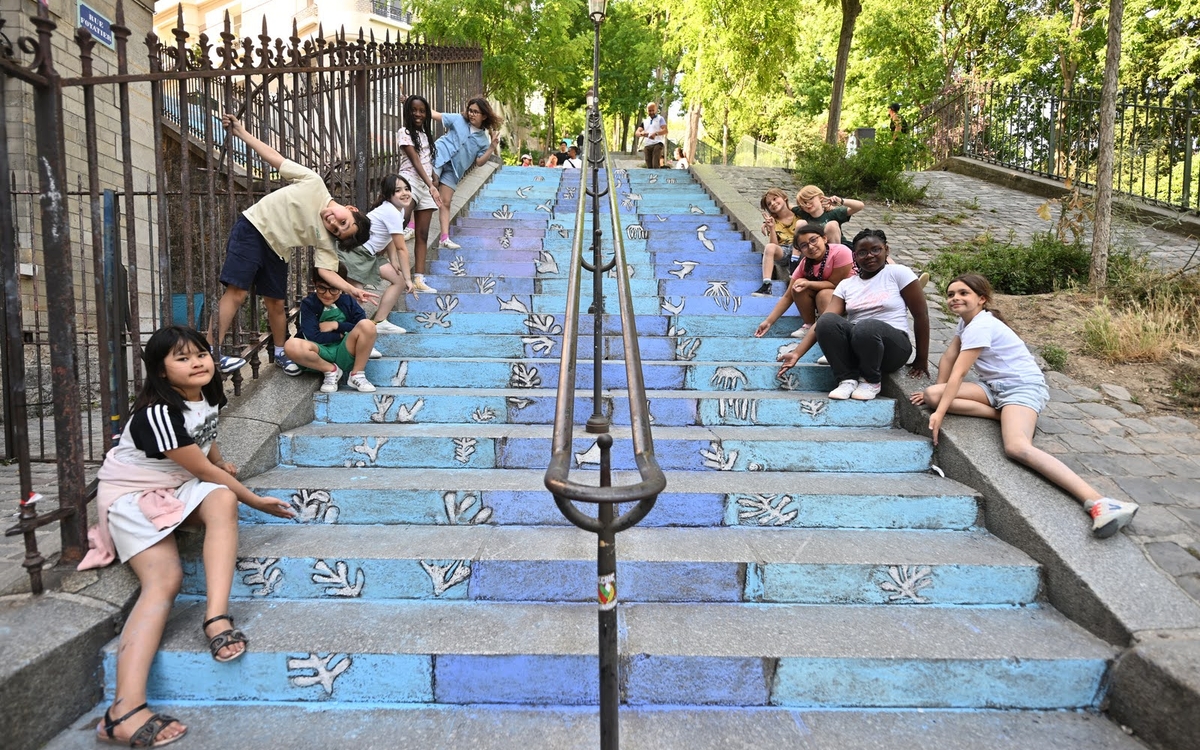 des enfants montrent leur peinture à la craie de la mer sur des escaliers de Montmartre