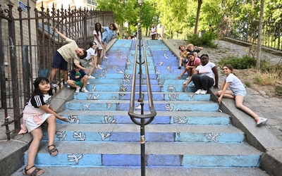 des enfants montrent leur peinture à la craie de la mer sur des escaliers de Montmartre