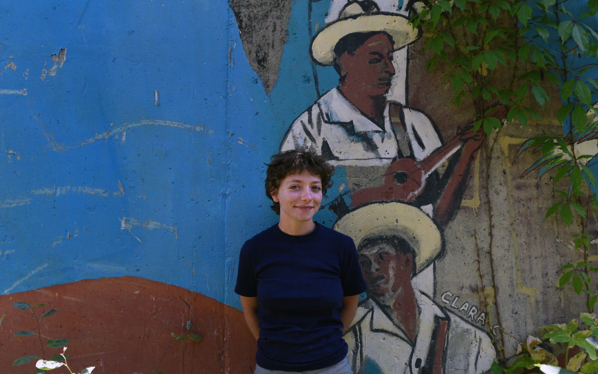 Portrait de Salomé, stagiaire devant la fresque extérieure de la Maison des réfugiés. 