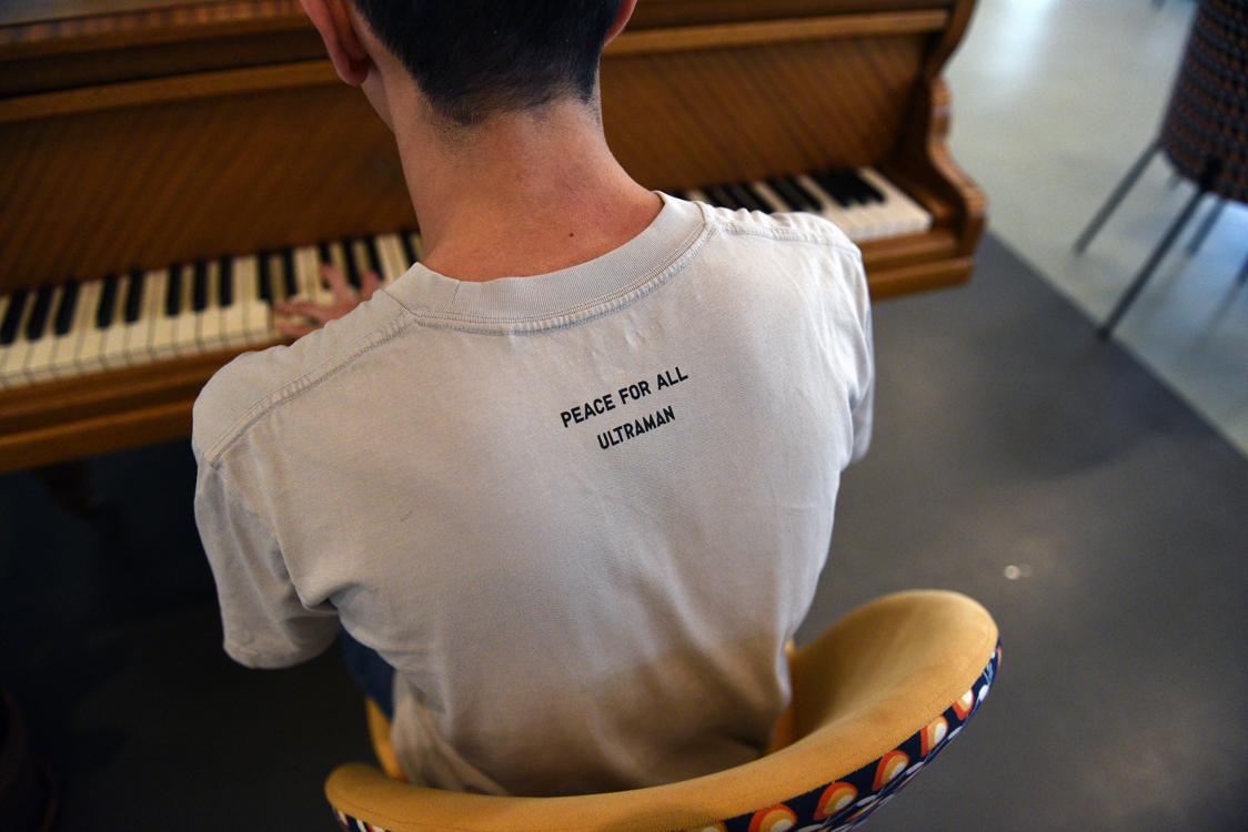 Keita, jeune pianiste, à l'oreille absolue, pris de dos en train de jouer sur le piano à queue de la Maison des réfugiés.