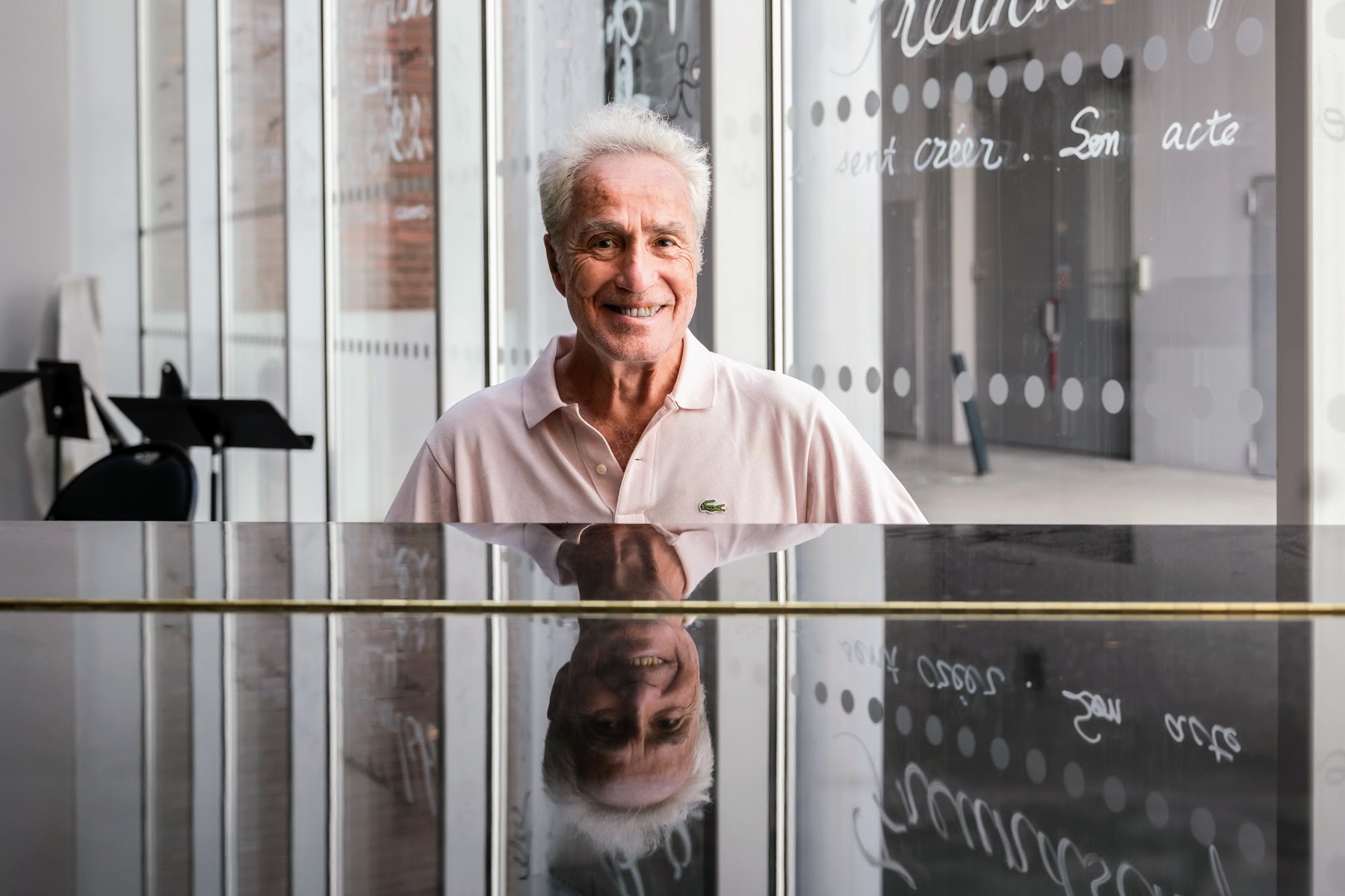 Un homme souriant, assis derrière un piano