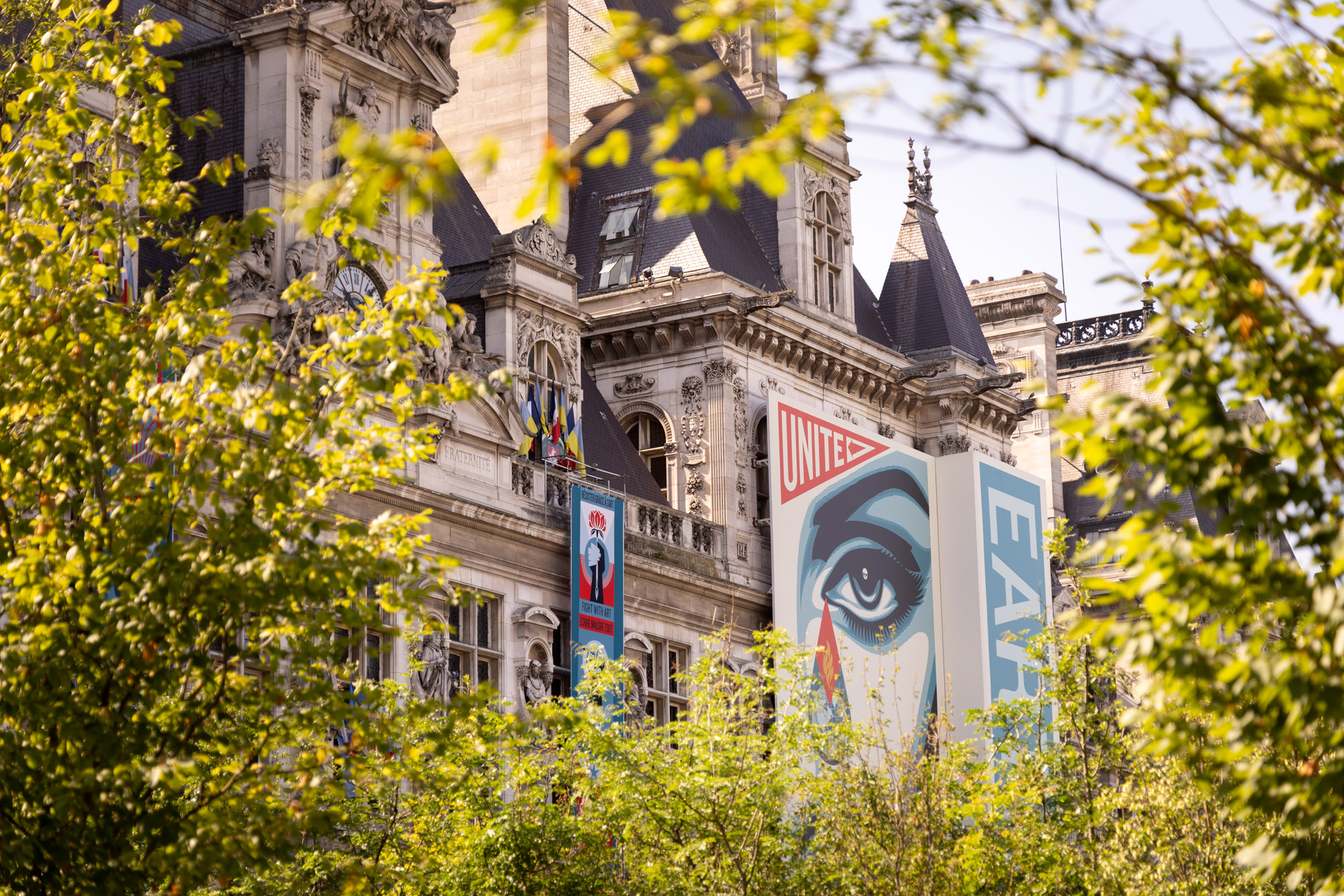 Façade de l'Hôtel de Ville avec l'affiche de l'artiste OBEY depuis la foret urbaine du parvis de l'Hôtel de Ville.