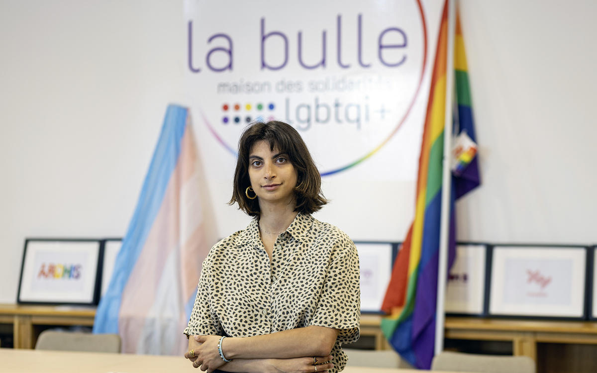 Femme qui se tient devant des drapeaux de la commauté queer