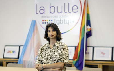 Femme qui se tient devant des drapeaux de la commauté queer