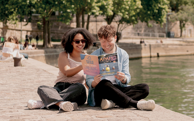 Deux personnes lisent le dernier magazine A Paris sur les quais de Seine.