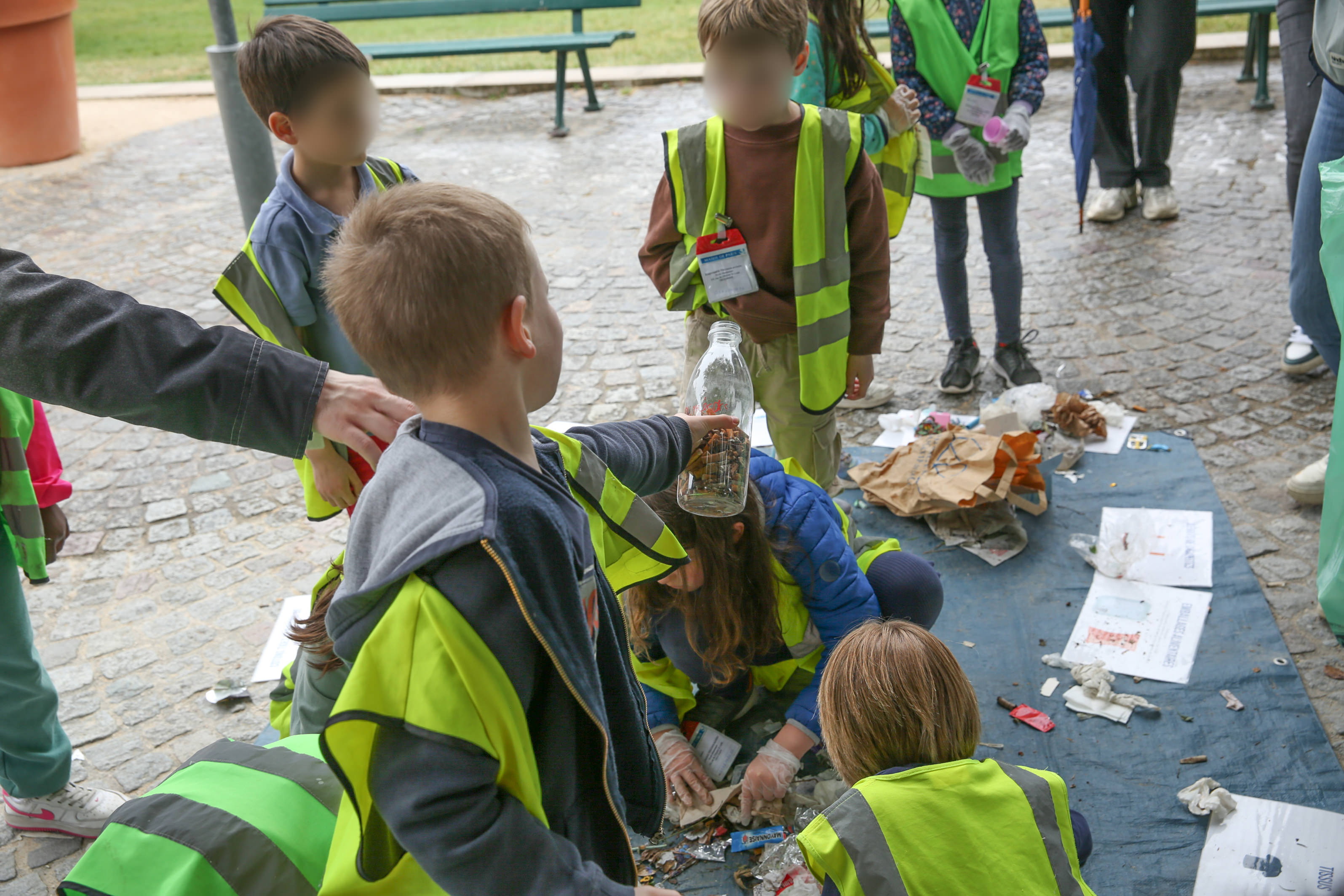 enfants qui montre la bouteille rempli de mégots ramassés