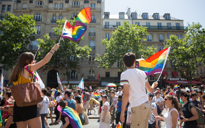 Deux personnes brandissant le drapeau LGBTQIA+ lors de la marche des fiertés.