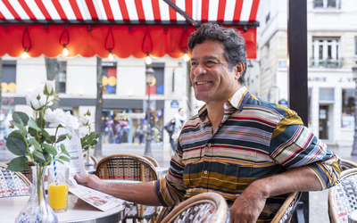 Rai, légende du football brésilien, attablé à une table dans un café parisien.