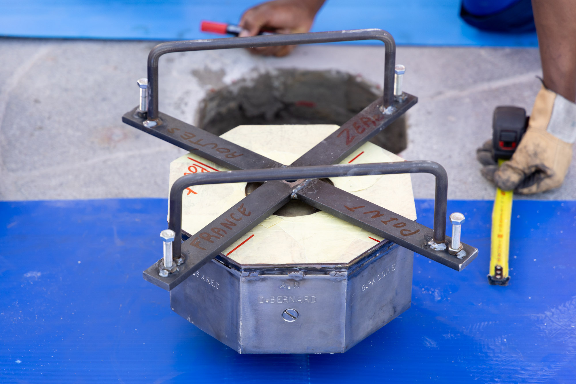 Une personne s'apprête à installer le nouveau point Zéro sur le parvis de Notre Dame.