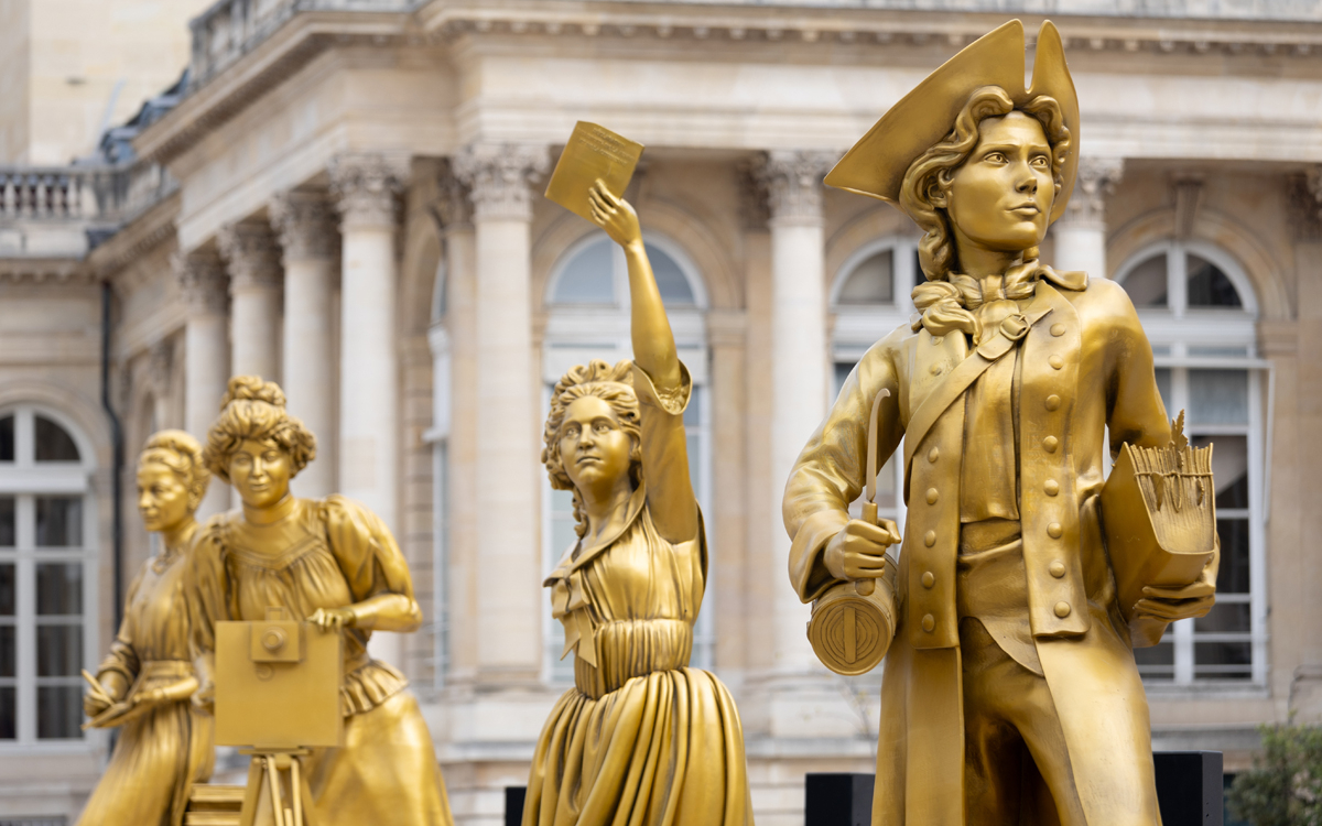 Les statues des femmes en or Jeanne Barret, Olympe de Gouges et Alice Guy devant l'Assemblée Nationale. 